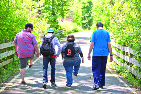 Three teen or young adult students and a teacher walking on a paved path