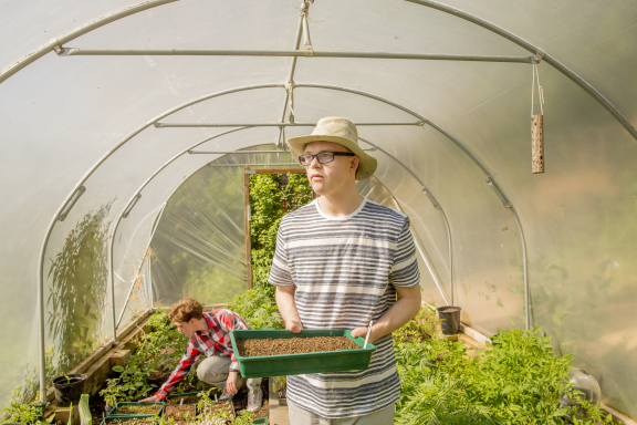 Two people farming in a greenhouse.