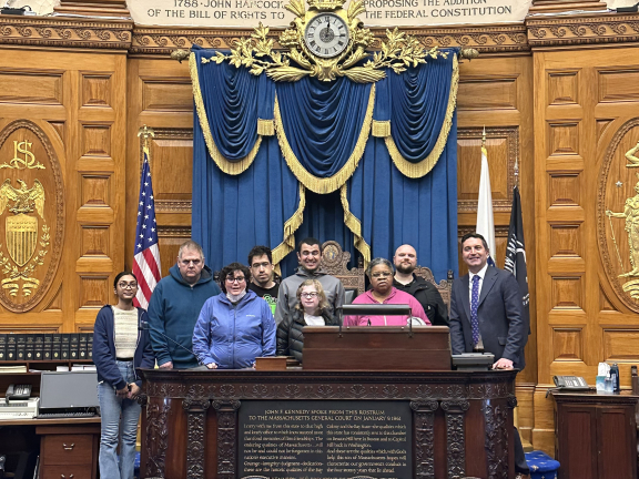 Group of adults standing behind a dais in the State House