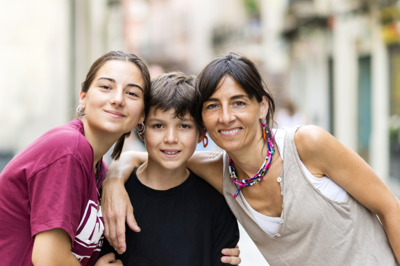 Happy family of three with a mom and two children embracing