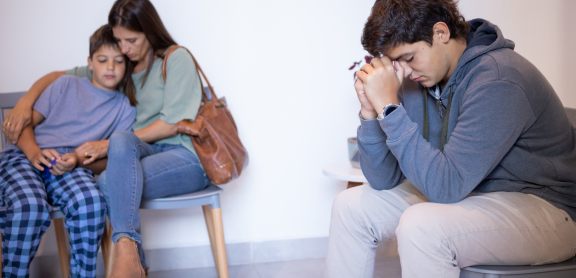 A family of three looks distraught in a waiting room