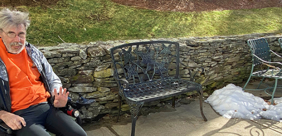 Jim sitting in his wheelchair outside smiling