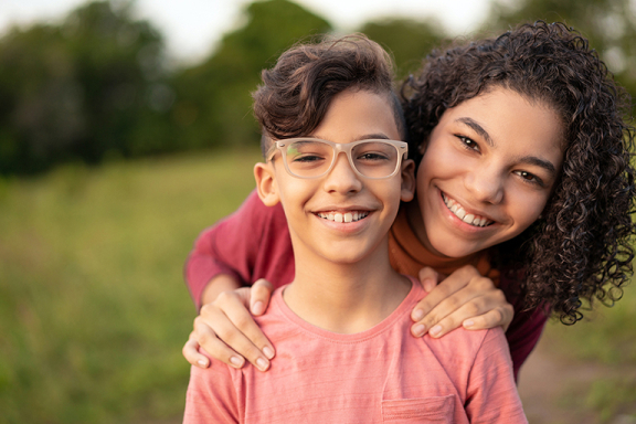Young brother and sister posing together smiling.