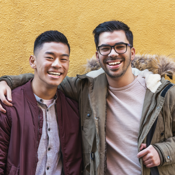 Two young adults with short dark hair smile at the camera